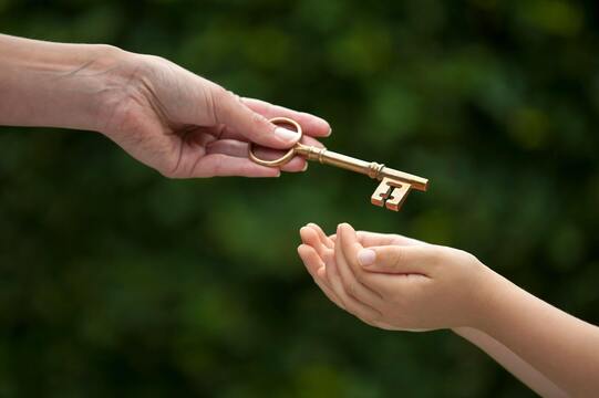 3 Manières dont l'épargne dans l'or peut profiter à vos enfants et à votre famille les parents commencent à épargner pour l'avenir de leurs enfants le plus tôt possible afin de leur constituer un filet de sécurité solide, représenté par l'image d'un adulte transmettant une clé en or à un enfant.