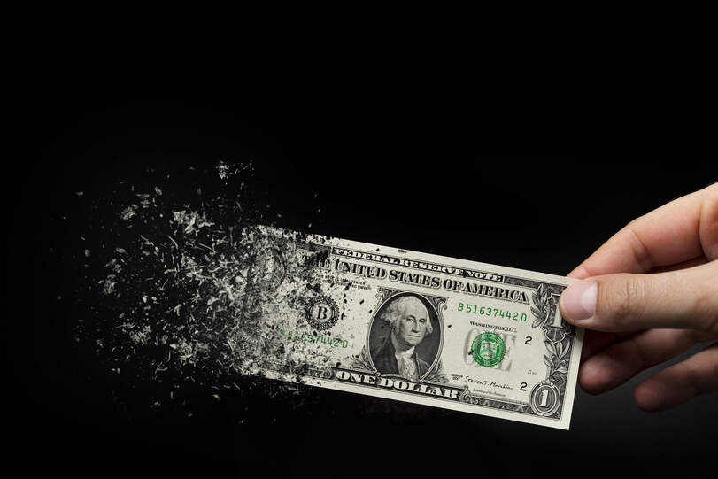 News-Woche: Gold erzielt beste Ergebnisse, Inflation droht Ein Dollarschein in der Hand eines Mannes vor schwarzem Hintergrund, der Inflation, schwächeren Dollar und russische Fonds signalisiert, die alle US-Dollar-Anlagen abstoßen