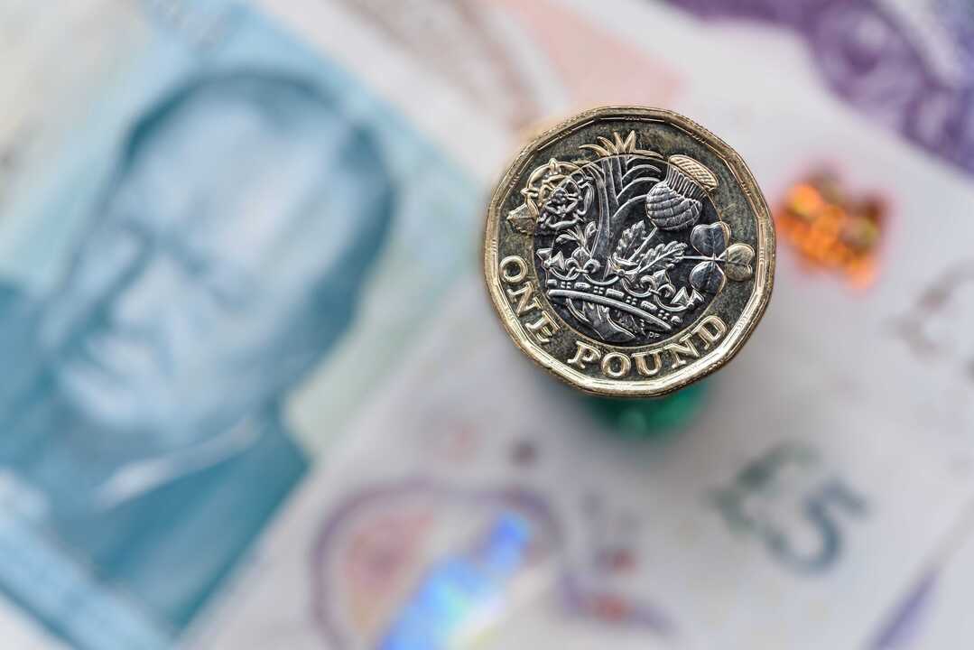 La settimana in breve: inflazione USA e UK, l’oro si riprende Una moneta da una sterlina con dietro una banconota da cinque sterline.