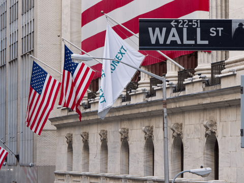 L’actu en bref : Les actions en hausse après la chute, la Chine s'attaque au bitcoin Gros plan d'un panneau de Wall Street à New York et du bâtiment de la bourse en arrière-plan avec des drapeaux américains