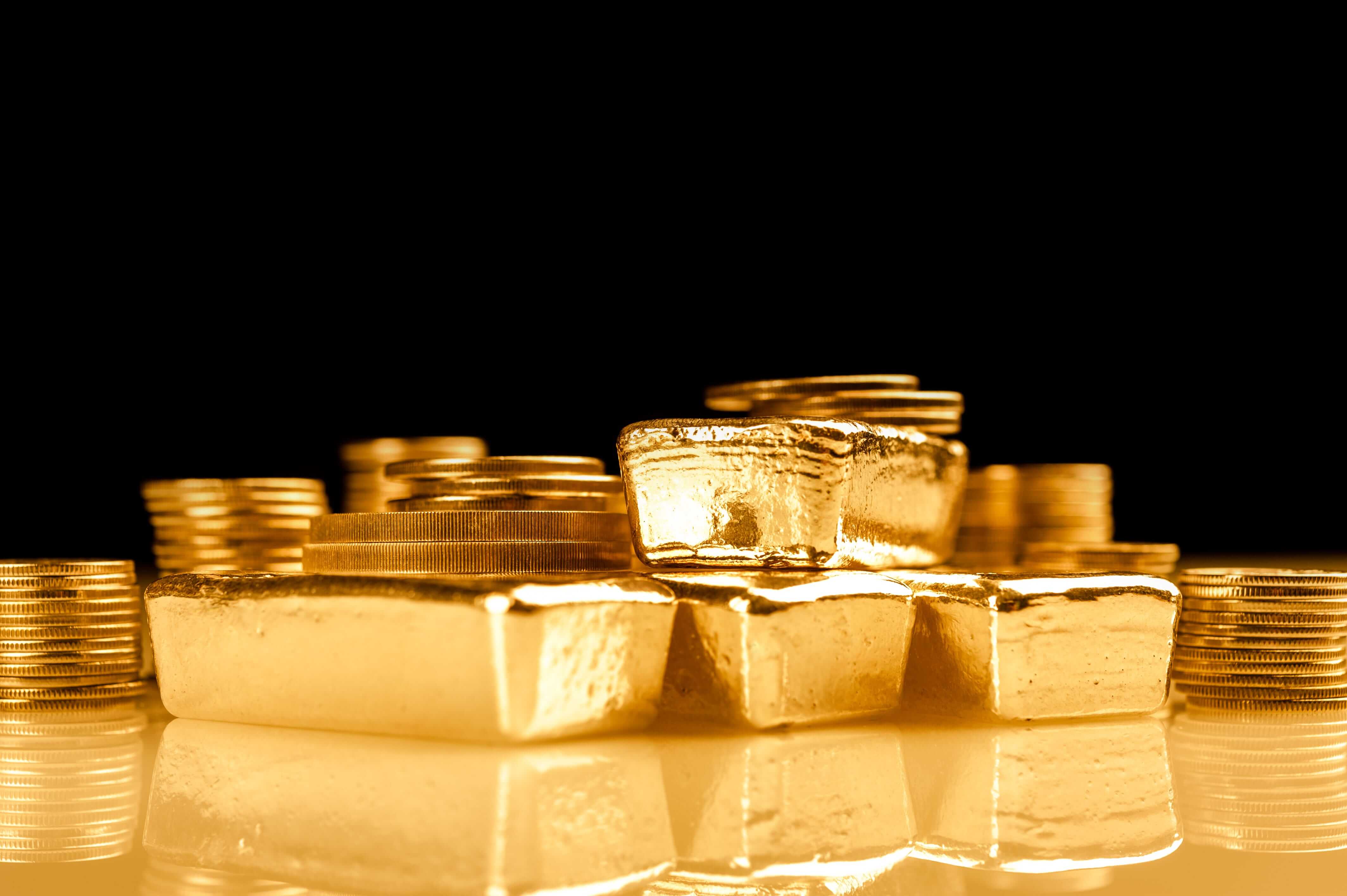 Fine gold bars and coins on the black background representing rising gold prices