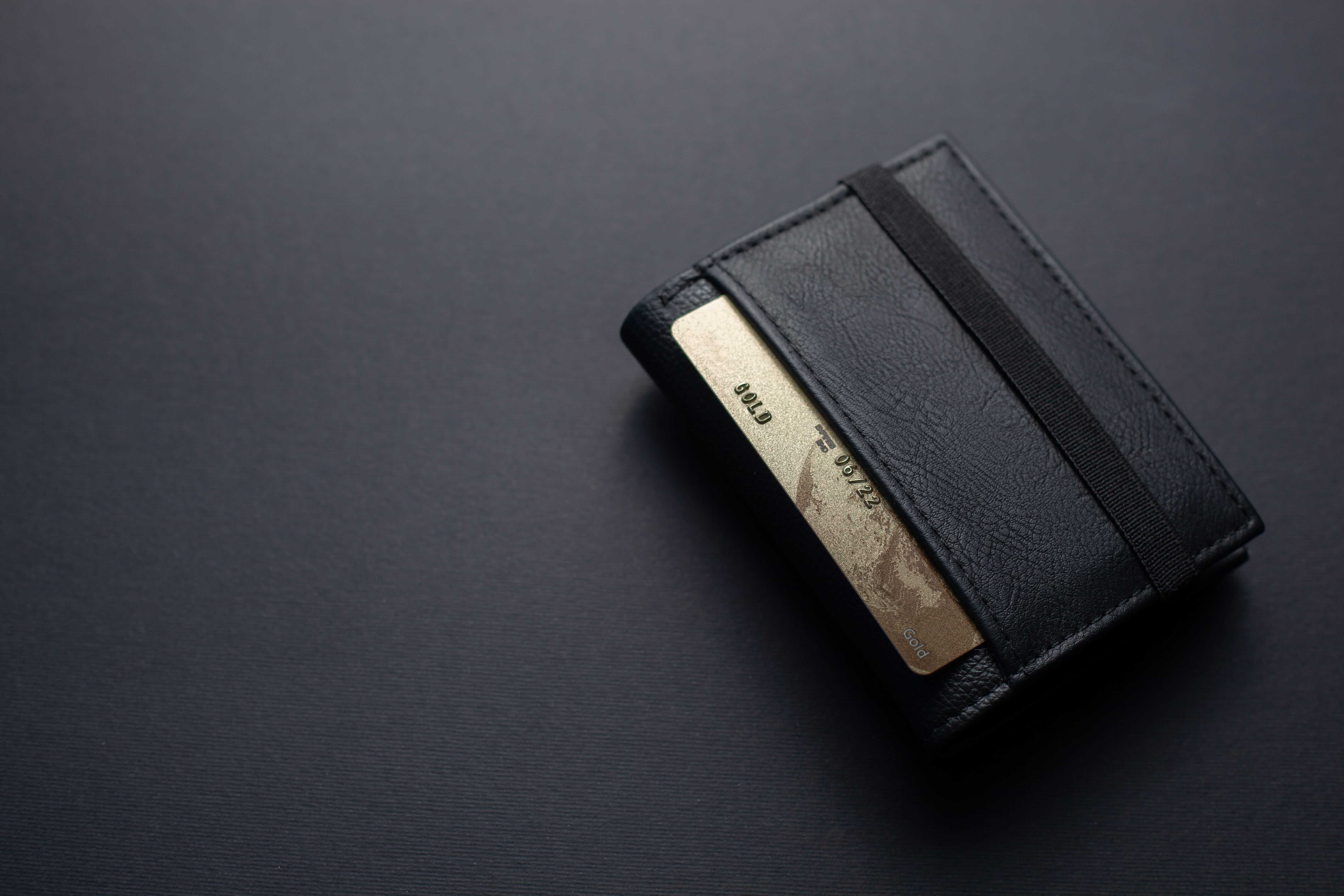 a golden credit card in a black wallet lying on a black surface