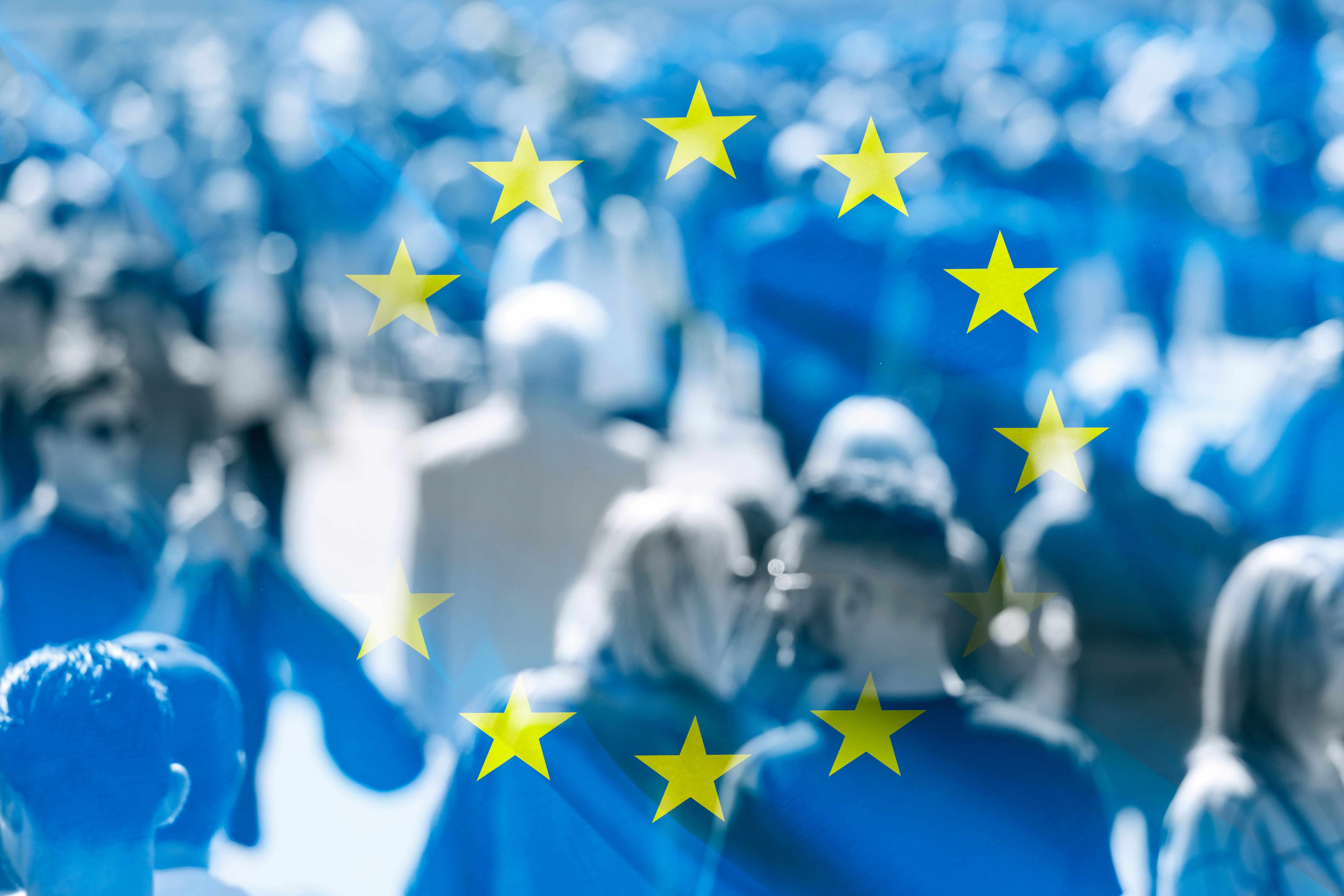 An EU flag with a blurred background image of people walking