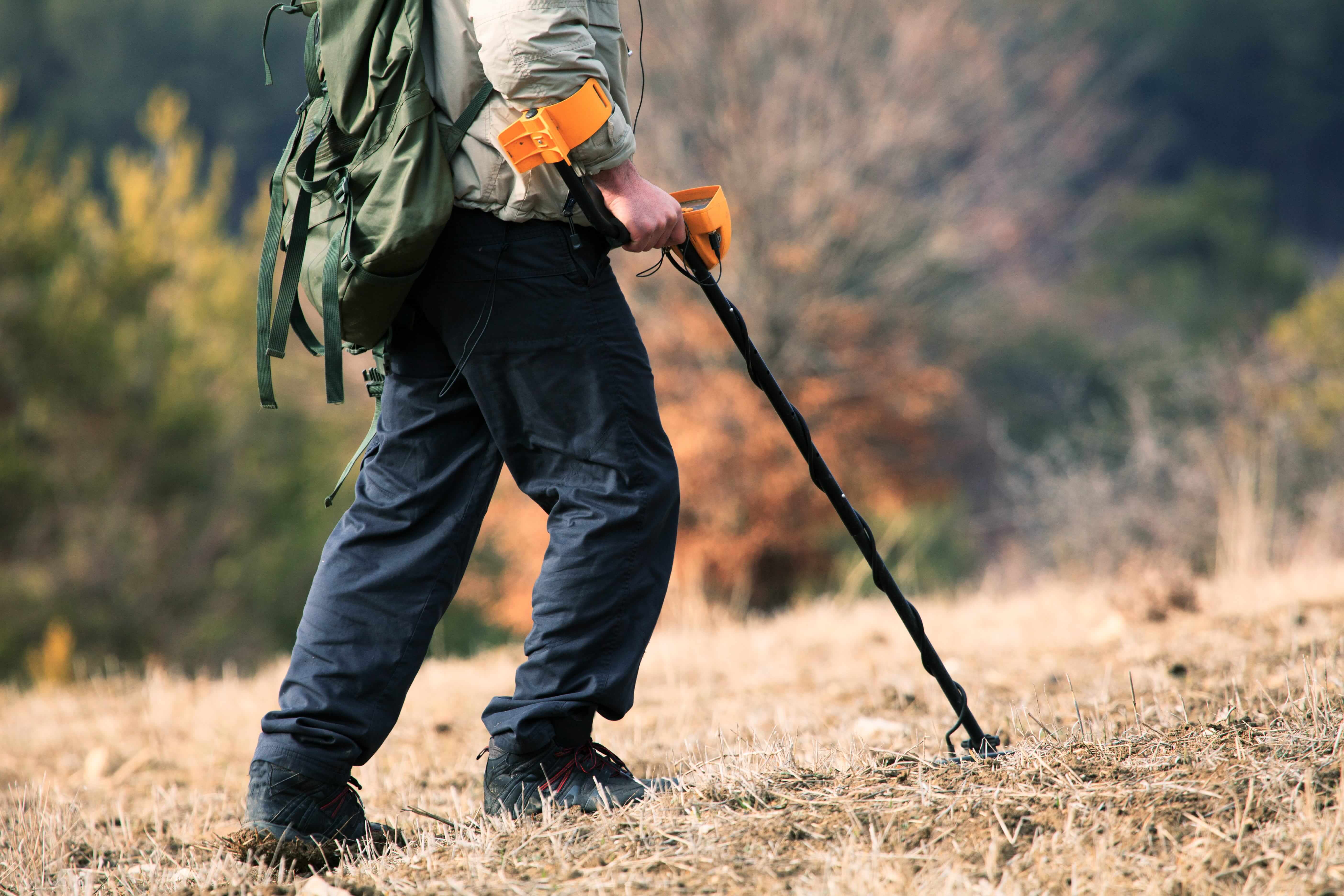 A man searching for gold with a metal detector