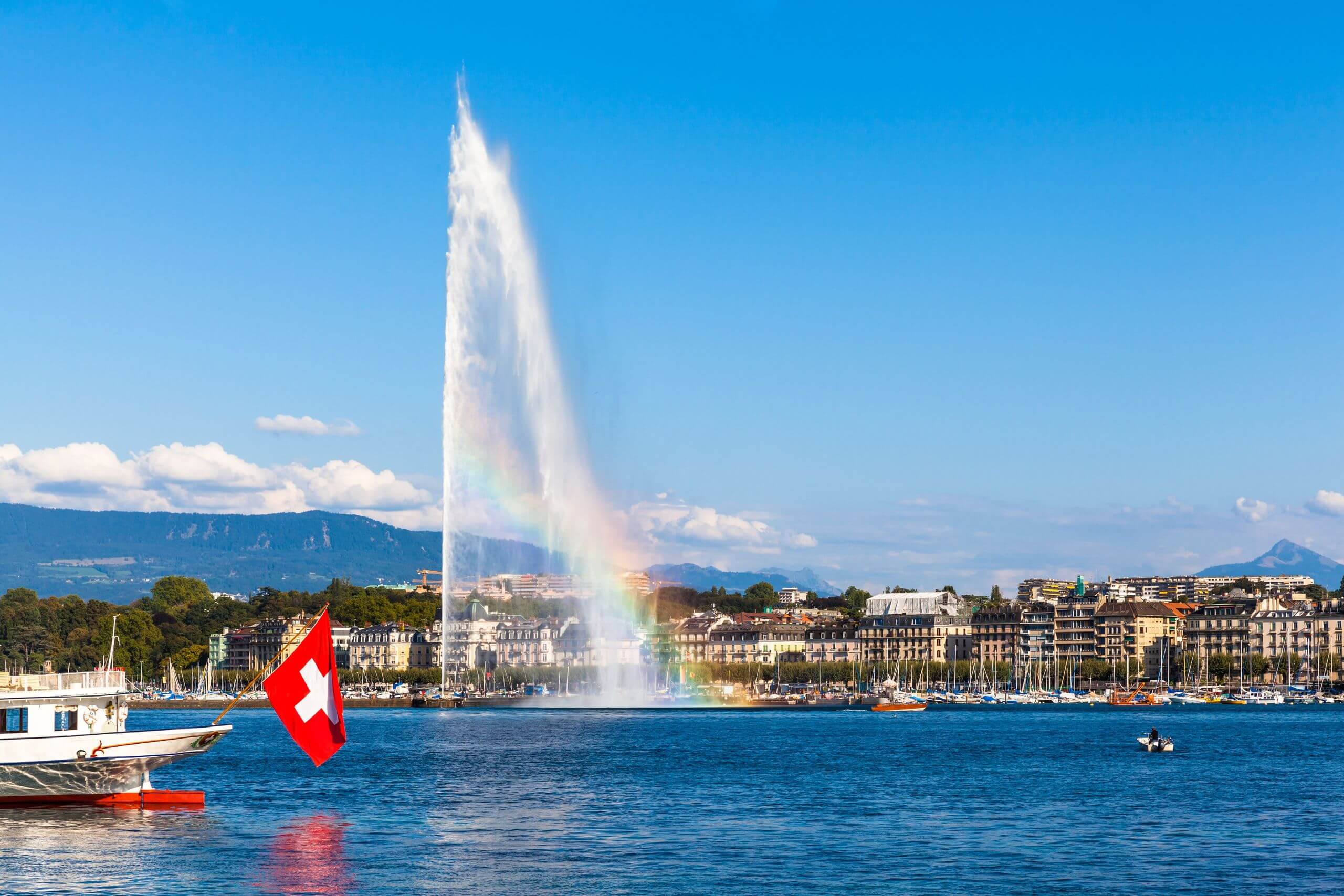 The famous Geneva fountain, and a boat with the Swiss flag on the Leman Lake