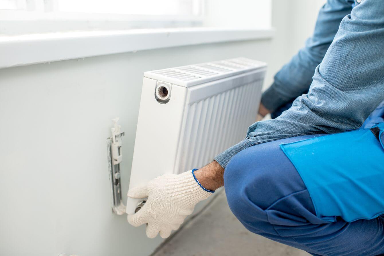 a man removing the radiator to hide his gold bars in inside the wall